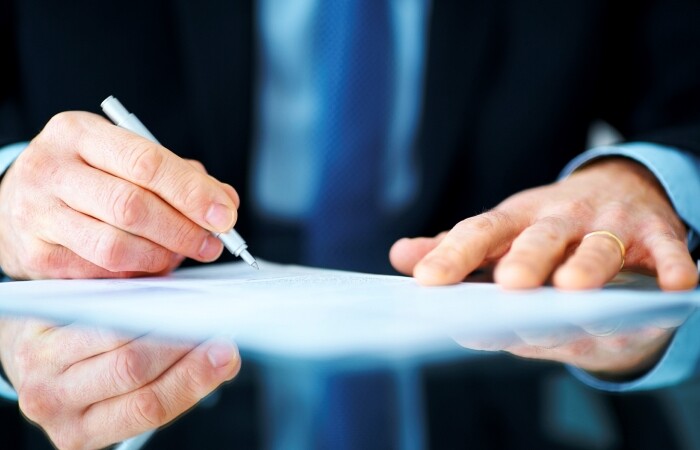 Business man hand signing on document at desk